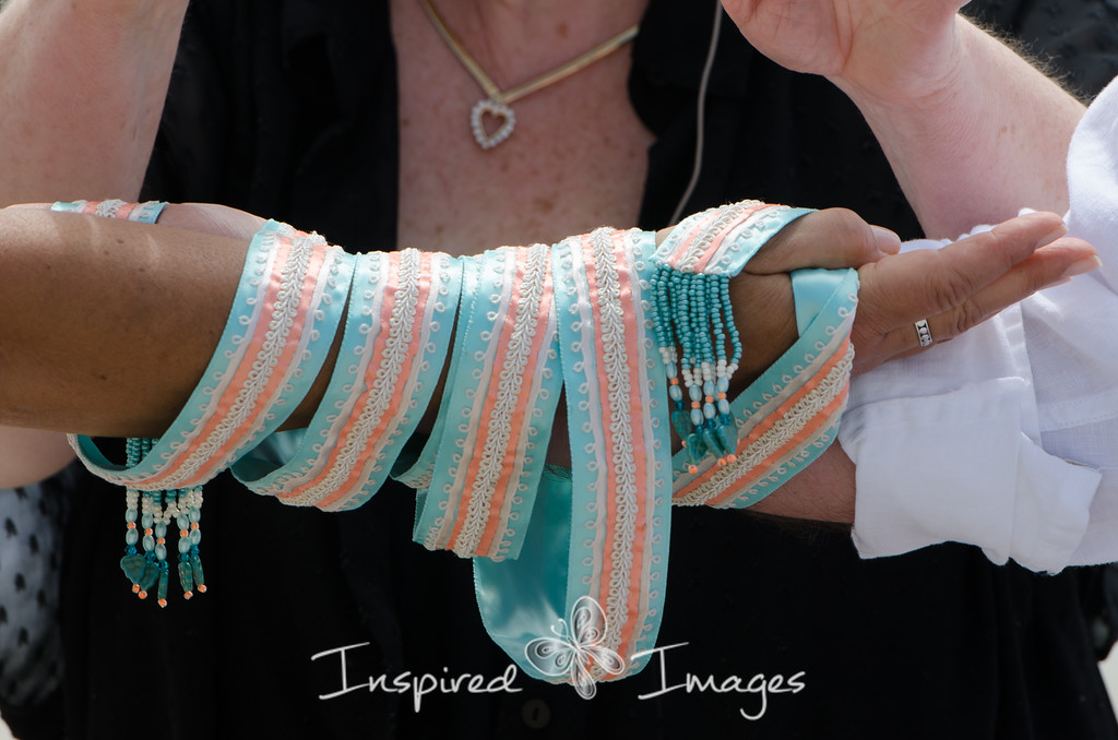 Wedding officiant binds a couples hands with a decorative cord