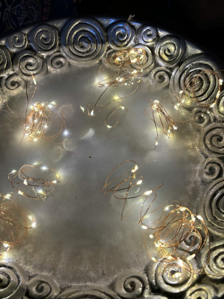 A pewter bowl filled with water and fairy lights for a Summer Solstice ritual