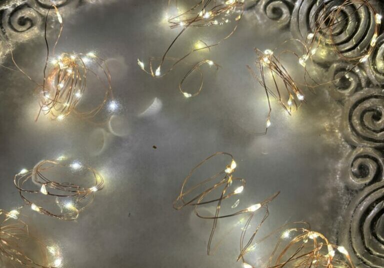 A pewter bowl filled with water and fairy lights for a Summer Solstice ritual